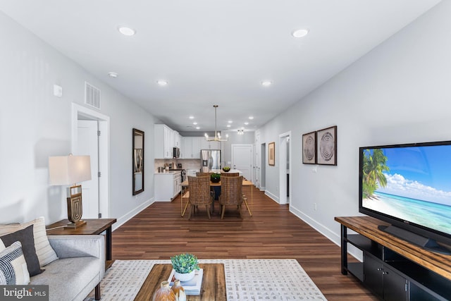 living area with dark wood-style floors, recessed lighting, baseboards, and an inviting chandelier