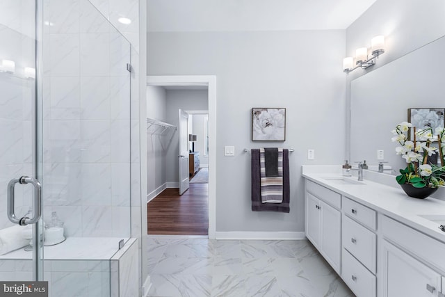 bathroom featuring a stall shower, marble finish floor, a sink, and baseboards