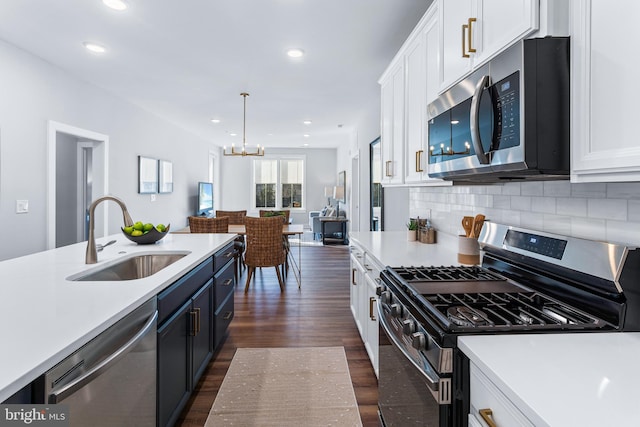 kitchen featuring dark wood-type flooring, a sink, white cabinets, light countertops, and appliances with stainless steel finishes