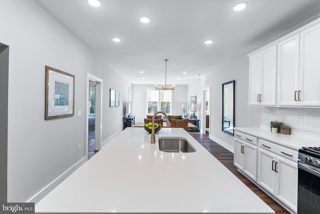 kitchen featuring a sink, white cabinets, light countertops, stainless steel range with gas cooktop, and an island with sink