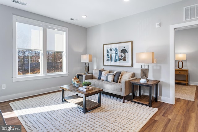 living room with visible vents, baseboards, and wood finished floors