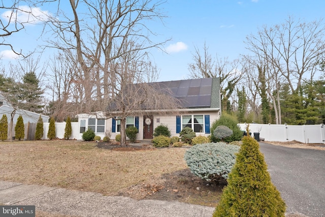 view of front of property with a gate, driveway, roof mounted solar panels, and fence