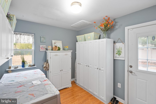 bedroom featuring light wood-style floors, baseboards, multiple windows, and visible vents