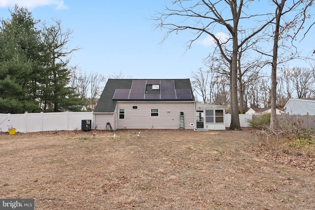 back of house with a fenced backyard, cooling unit, a sunroom, and roof mounted solar panels