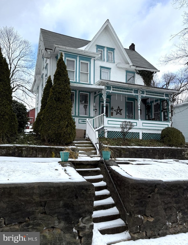 view of front facade with covered porch and a chimney