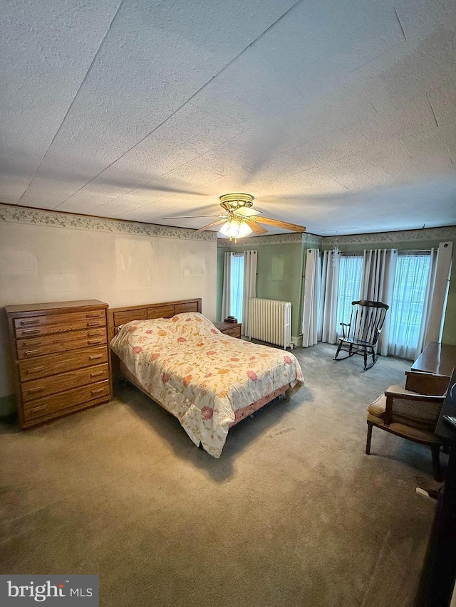 bedroom with carpet floors, radiator, ceiling fan, and a textured ceiling