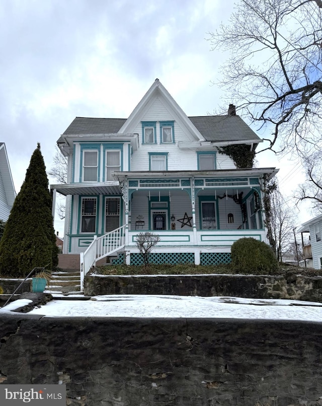 view of front facade featuring covered porch and a chimney