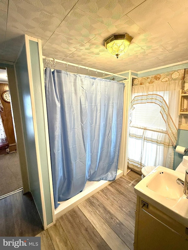 full bath with vanity, a shower with shower curtain, and wood finished floors