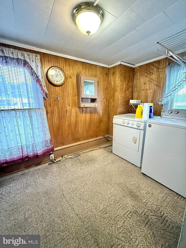 clothes washing area featuring crown molding, laundry area, washing machine and dryer, and wooden walls