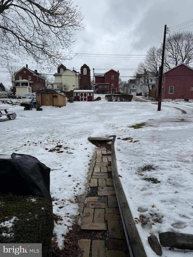 snowy yard featuring an outdoor structure and a storage shed