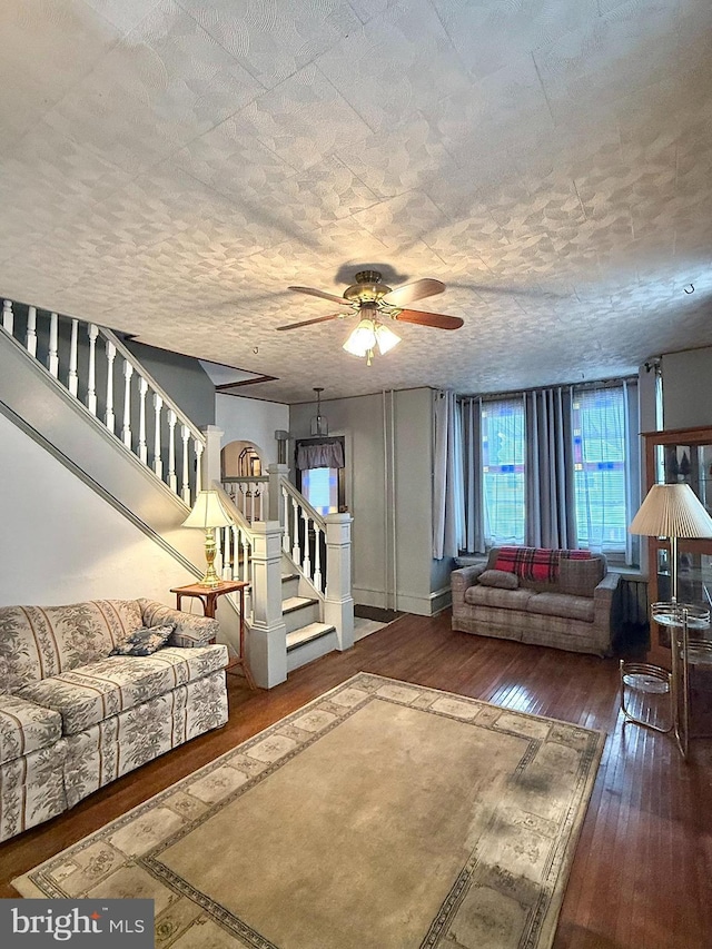 living area featuring ceiling fan, hardwood / wood-style floors, stairway, and baseboards