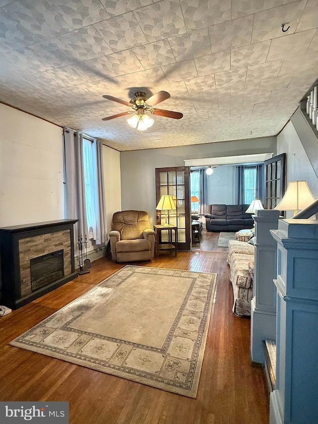 living room with ceiling fan, dark wood-style flooring, a fireplace, and stairs