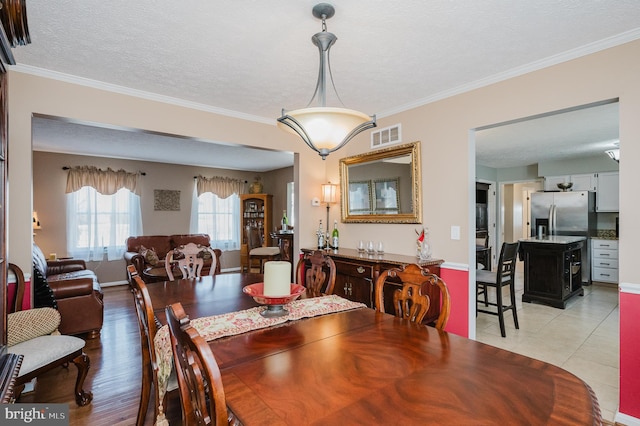 dining room with light tile patterned floors, crown molding, visible vents, and a textured ceiling