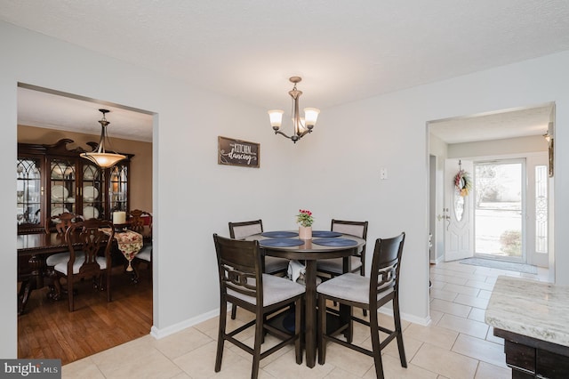 dining area featuring a notable chandelier, a textured ceiling, baseboards, and light tile patterned floors