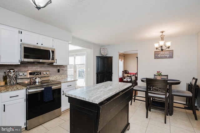 kitchen with pendant lighting, stainless steel appliances, tasteful backsplash, light tile patterned flooring, and white cabinets