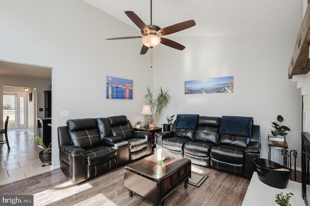 living area featuring a ceiling fan, baseboards, a high ceiling, and wood finished floors