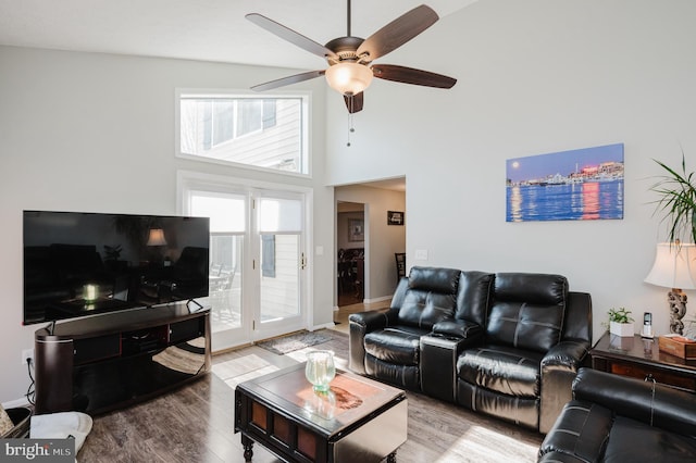 living room with ceiling fan, a high ceiling, and wood finished floors