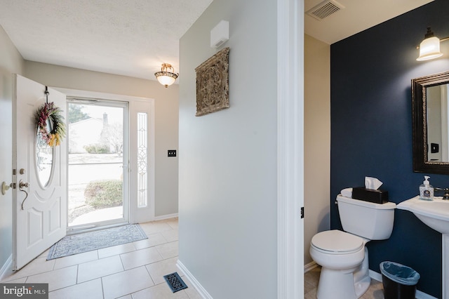 foyer entrance featuring baseboards, visible vents, a textured ceiling, and light tile patterned flooring