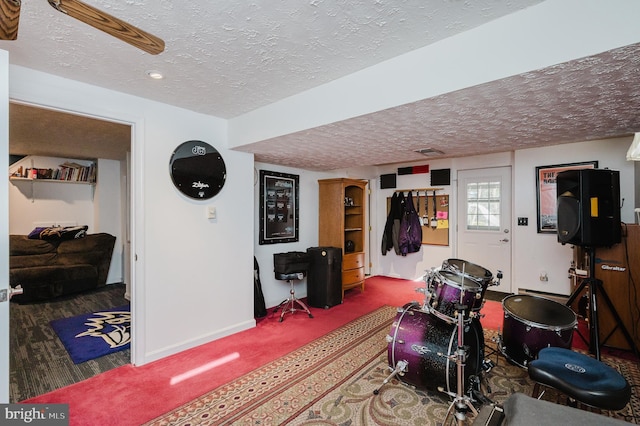 workout area featuring a textured ceiling, carpet, and baseboards