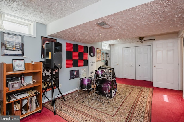 rec room with a textured ceiling, ceiling fan, visible vents, baseboards, and carpet