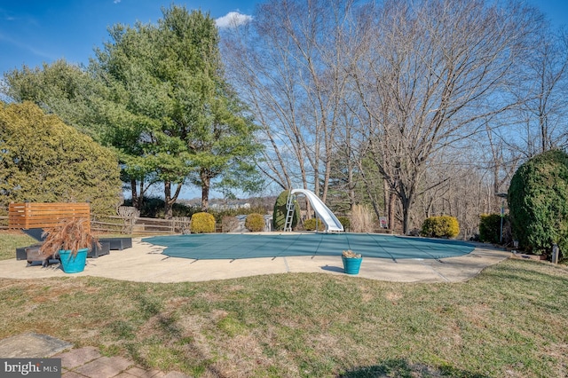 view of swimming pool featuring a patio, a water slide, fence, and a covered pool