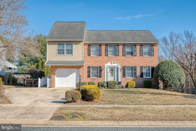 colonial home with brick siding, concrete driveway, an attached garage, fence, and a front lawn