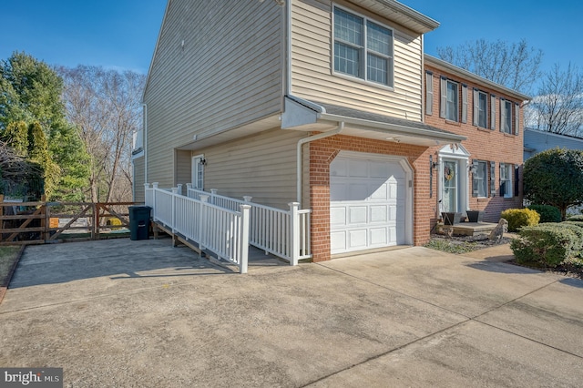 view of front of house featuring driveway, a garage, fence, and brick siding