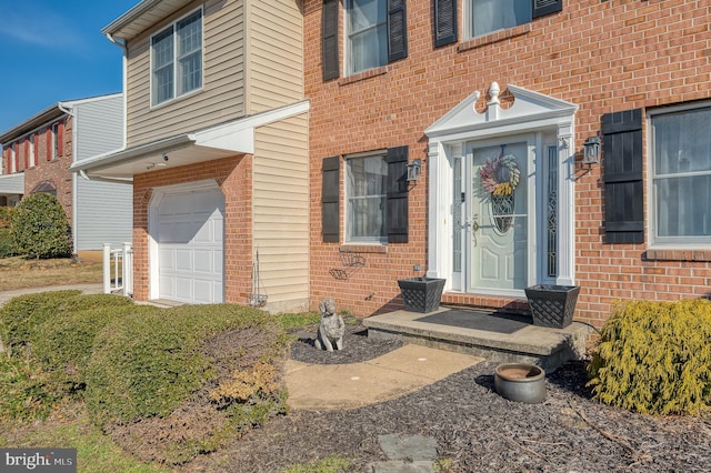 doorway to property with a garage and brick siding