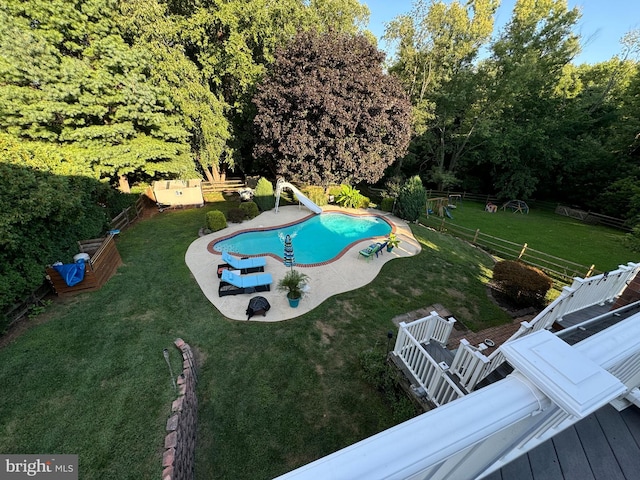 view of pool with a deck, a water slide, a fenced backyard, a lawn, and a fenced in pool