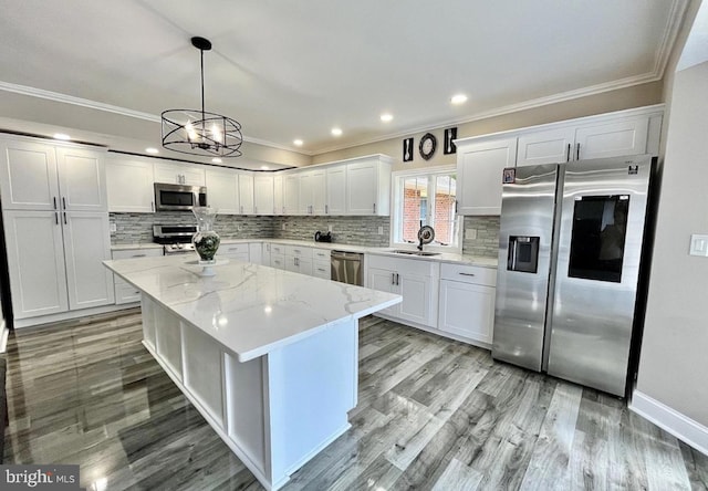 kitchen with a kitchen island, stainless steel appliances, light wood-style floors, white cabinetry, and a sink