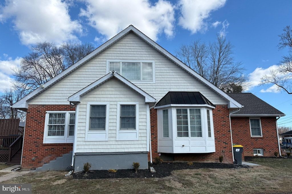 back of property with metal roof, brick siding, and a standing seam roof