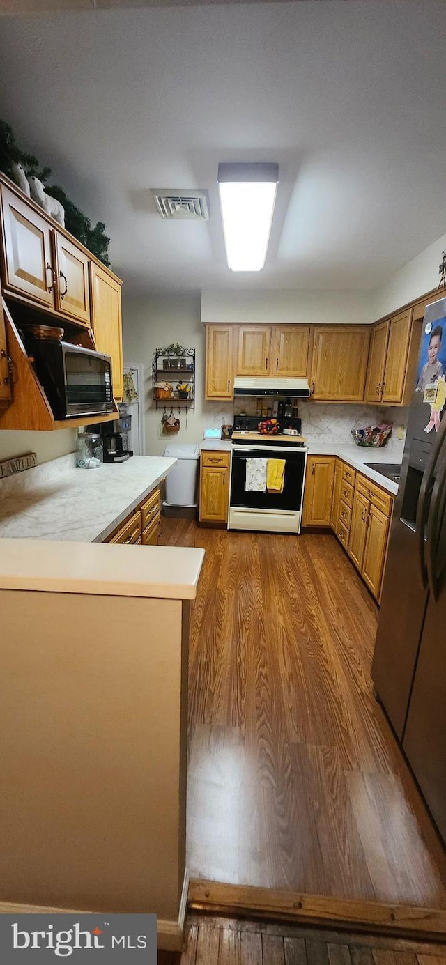 kitchen with dark wood-style floors, white range with electric stovetop, light countertops, visible vents, and stainless steel fridge with ice dispenser