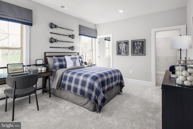 carpeted bedroom with a walk in closet, visible vents, and baseboards