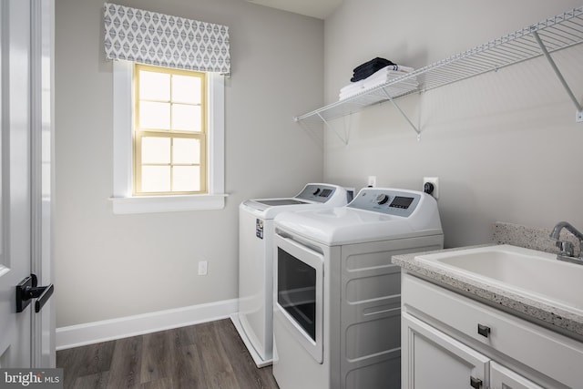 laundry area featuring cabinet space, baseboards, washer and clothes dryer, dark wood-type flooring, and a sink