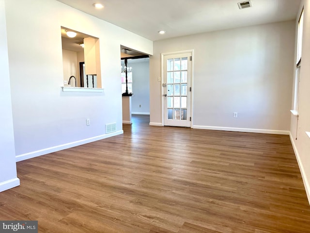 empty room featuring visible vents, baseboards, and wood finished floors