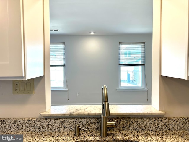 room details with light stone countertops, white cabinetry, and a sink