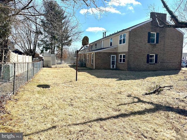 exterior space featuring brick siding, a lawn, and a fenced backyard