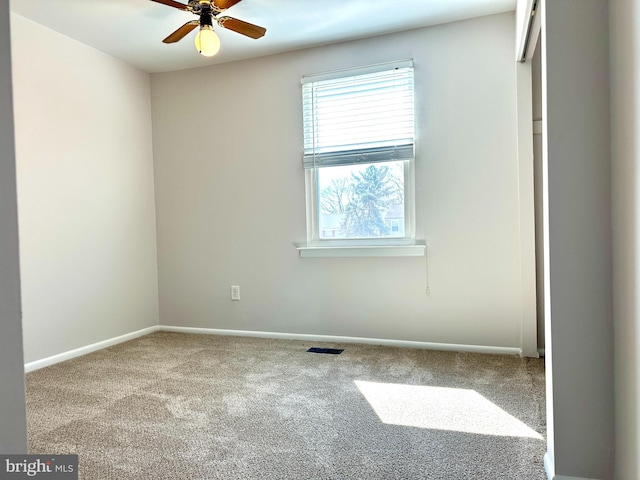 empty room featuring a ceiling fan, carpet, visible vents, and baseboards