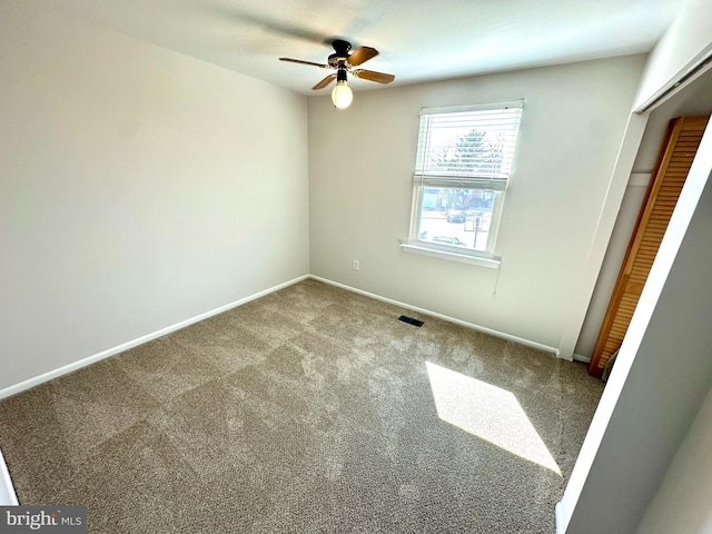 unfurnished bedroom featuring carpet flooring, a ceiling fan, visible vents, baseboards, and a closet