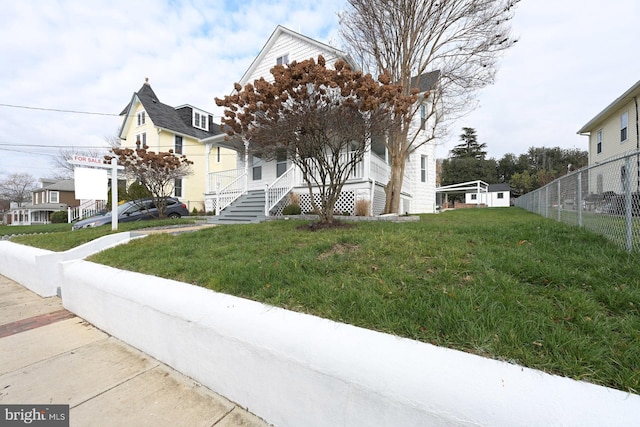 view of front of house featuring a front yard, covered porch, and fence