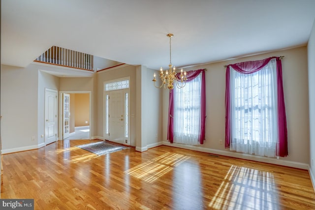 entrance foyer featuring a notable chandelier, baseboards, and wood finished floors