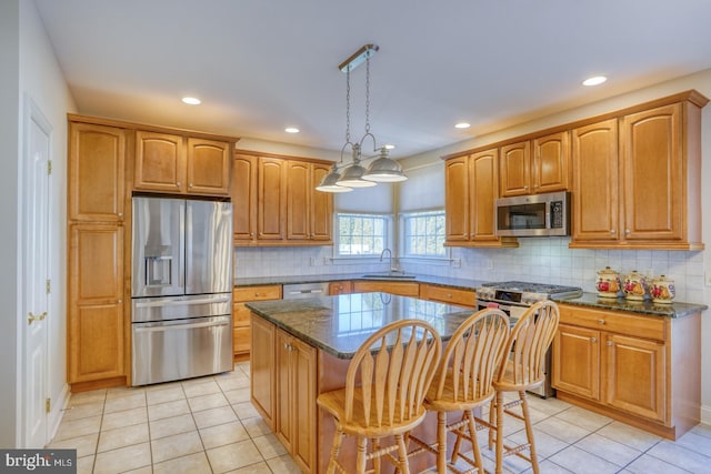 kitchen featuring light tile patterned floors, stainless steel appliances, a kitchen island, and a sink