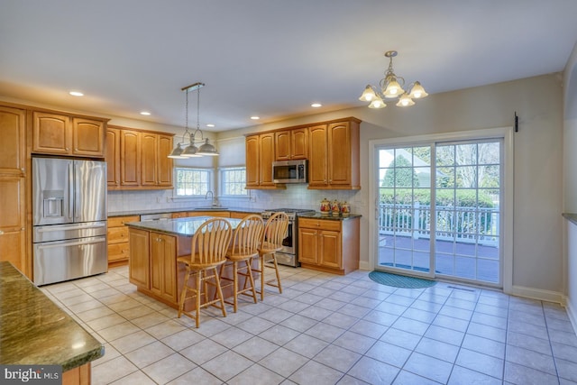 kitchen with decorative backsplash, appliances with stainless steel finishes, light tile patterned flooring, a sink, and a kitchen breakfast bar