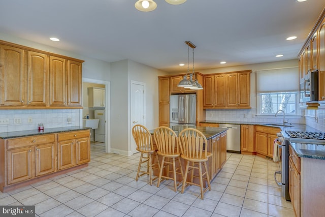 kitchen with light tile patterned floors, stainless steel appliances, a breakfast bar, a kitchen island, and a sink