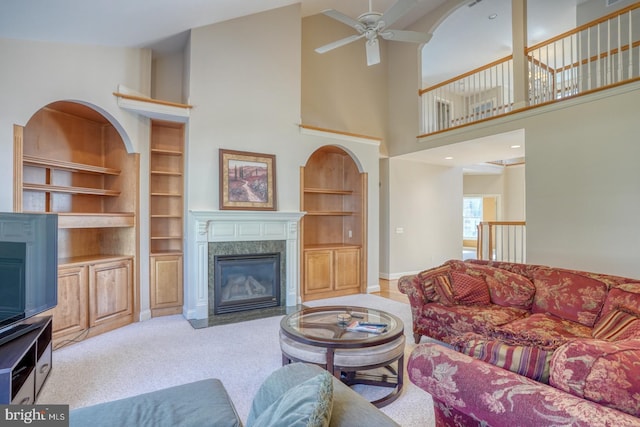 living room with ceiling fan, a fireplace, carpet flooring, and built in features