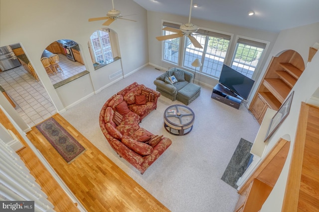 living area featuring baseboards, visible vents, a ceiling fan, a towering ceiling, and recessed lighting