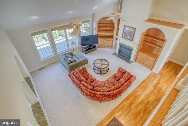 living room featuring a fireplace, a ceiling fan, baseboards, visible vents, and built in features