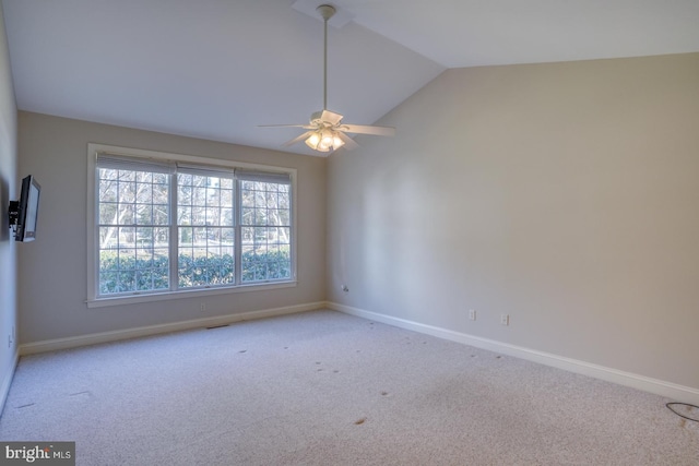 carpeted empty room featuring a ceiling fan, vaulted ceiling, and baseboards