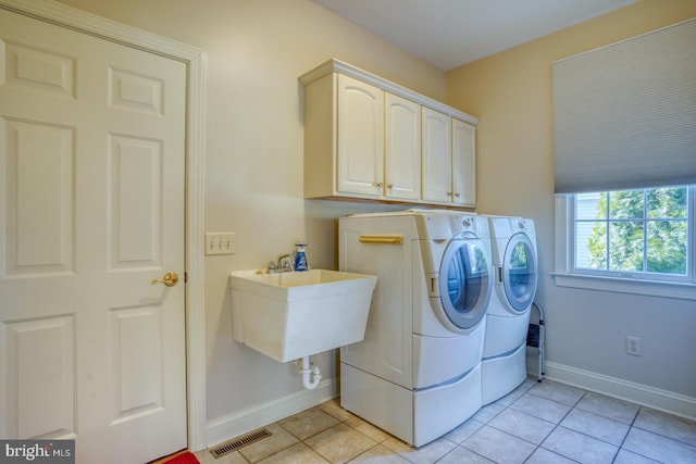 laundry room with light tile patterned floors, cabinet space, visible vents, separate washer and dryer, and baseboards