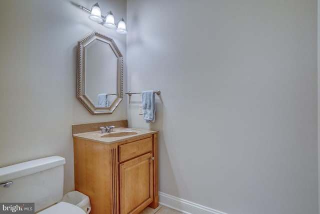 bathroom with vanity, toilet, and baseboards